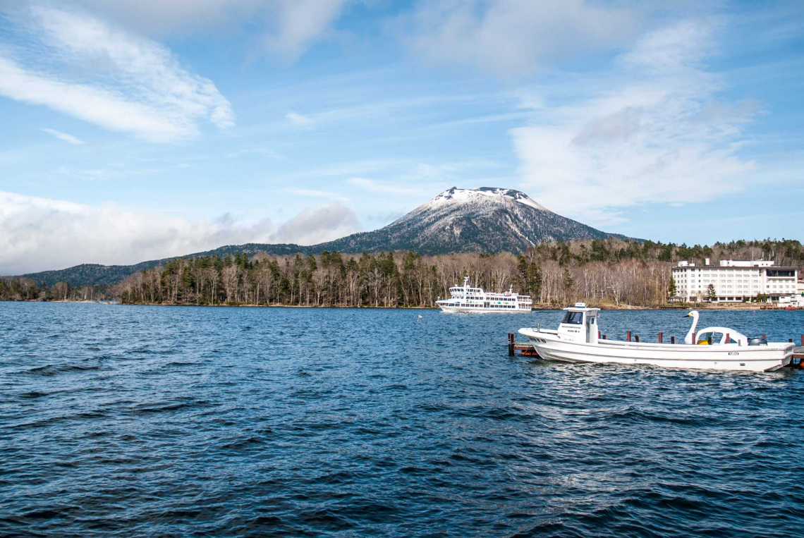 lake akan in with boats, hotel and mt. Oakan in the background spring hokaido japan